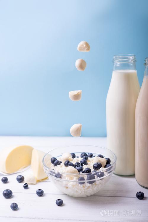 蓝莓和乳制品产品交替爱上马苏里拉着蓝色背景木制白色桌子上的.竖拍